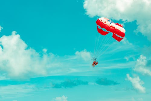 Photo of Two People Riding a Red and White Parachute