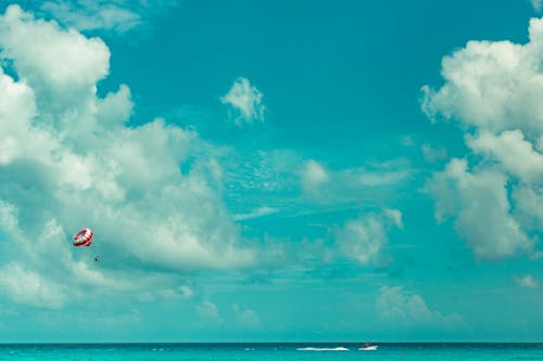 Orang Parasailing Di Bawah Awan Putih Dan Langit Biru