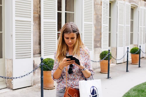 Free Woman Holding Smartphone Near Building Stock Photo