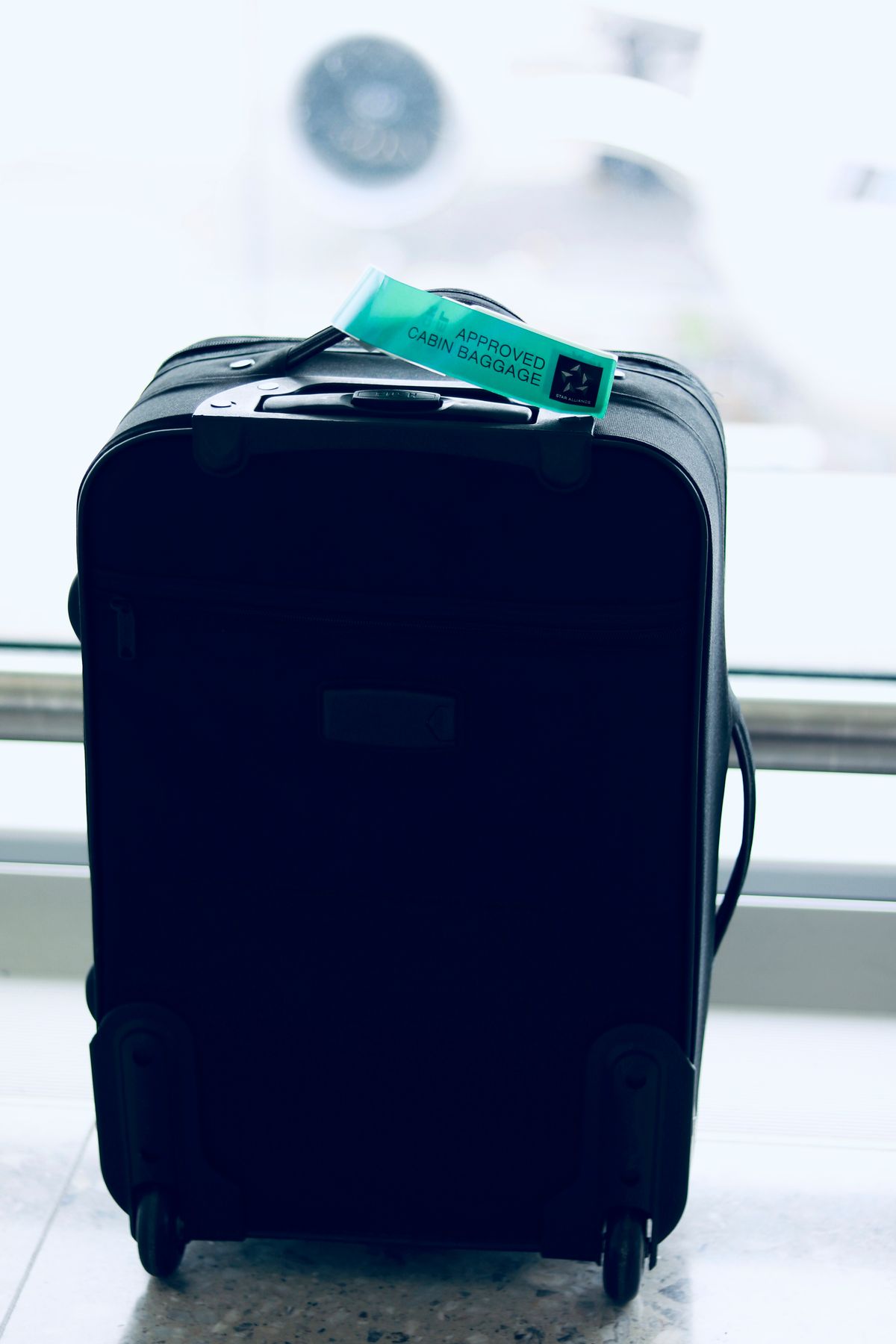 A cabin bag with an "approved cabin baggage" tag attached to the handle