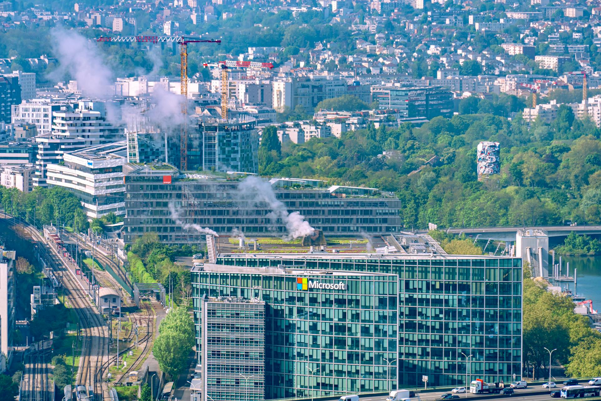 Aerial cityscape featuring the Microsoft Building and Seine River in Paris, showcasing urban architecture and lush greenery.