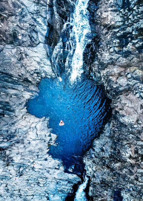 Stunning aerial shot of a crystal-clear blue waterfall pool surrounded by rocky terrain in Australia.