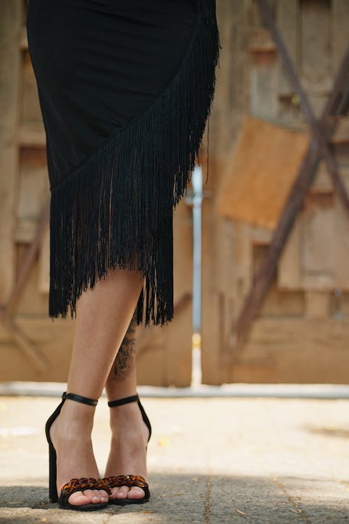 A woman in black skirt and heels with a fringe