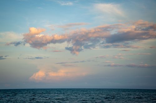 Free Calm ocean view at sunset with soft clouds on the horizon, capturing nature's tranquility. Stock Photo