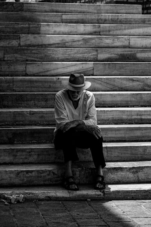 A man sitting on some steps with a hat on