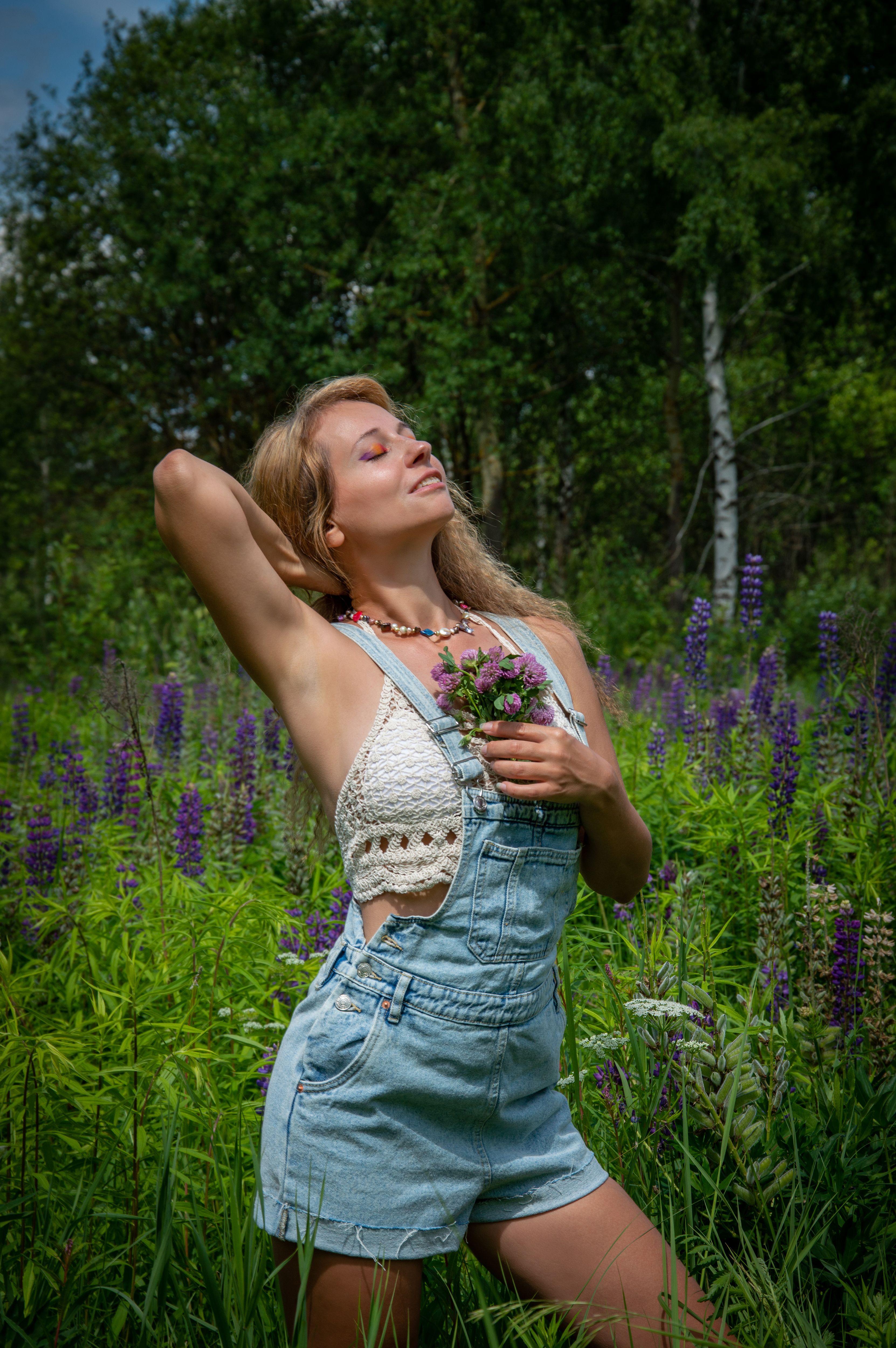 A woman in overalls is standing in a field of flowers · Free Stock Photo