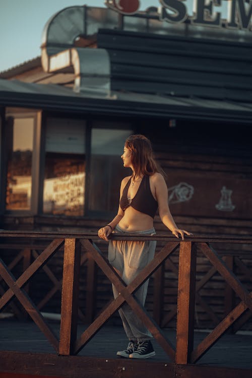 A woman in a sports bra and shorts standing on a wooden railing