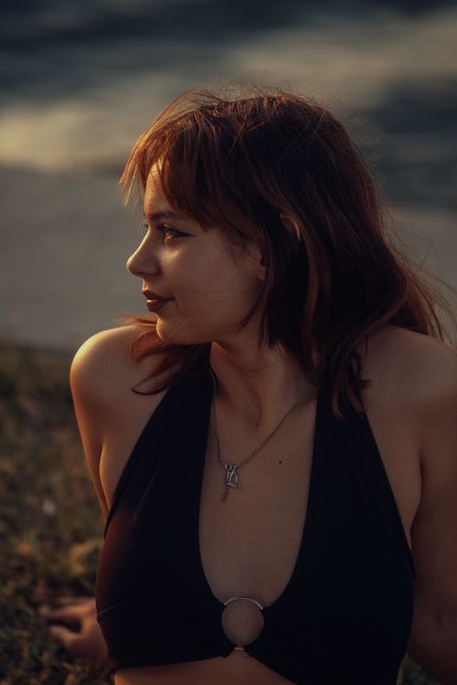 Free Portrait of a woman with brown hair and necklace during sunset, outdoors. Stock Photo