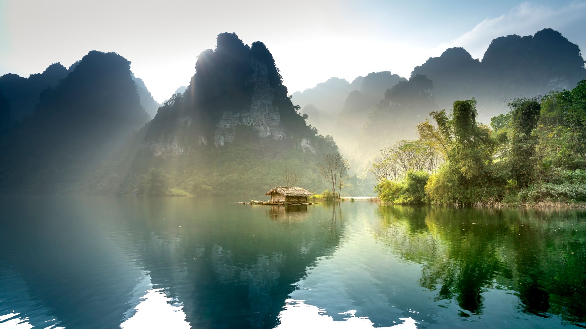 Stunning sunrise over a peaceful lake surrounded by lush mountains in Thượng Lâm, Vietnam.