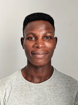 浅色背景下，一位微笑的非裔美国男子特写肖像