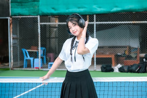 Girl Wearing Headphones on a Tennis Court 