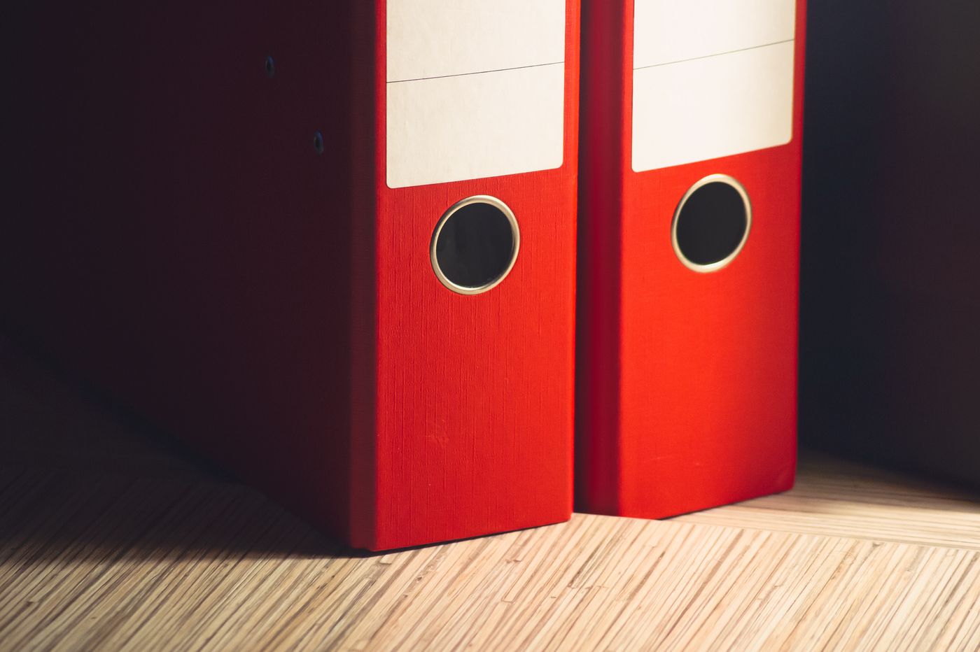 Deux classeurs rouges sur un bureau en bois