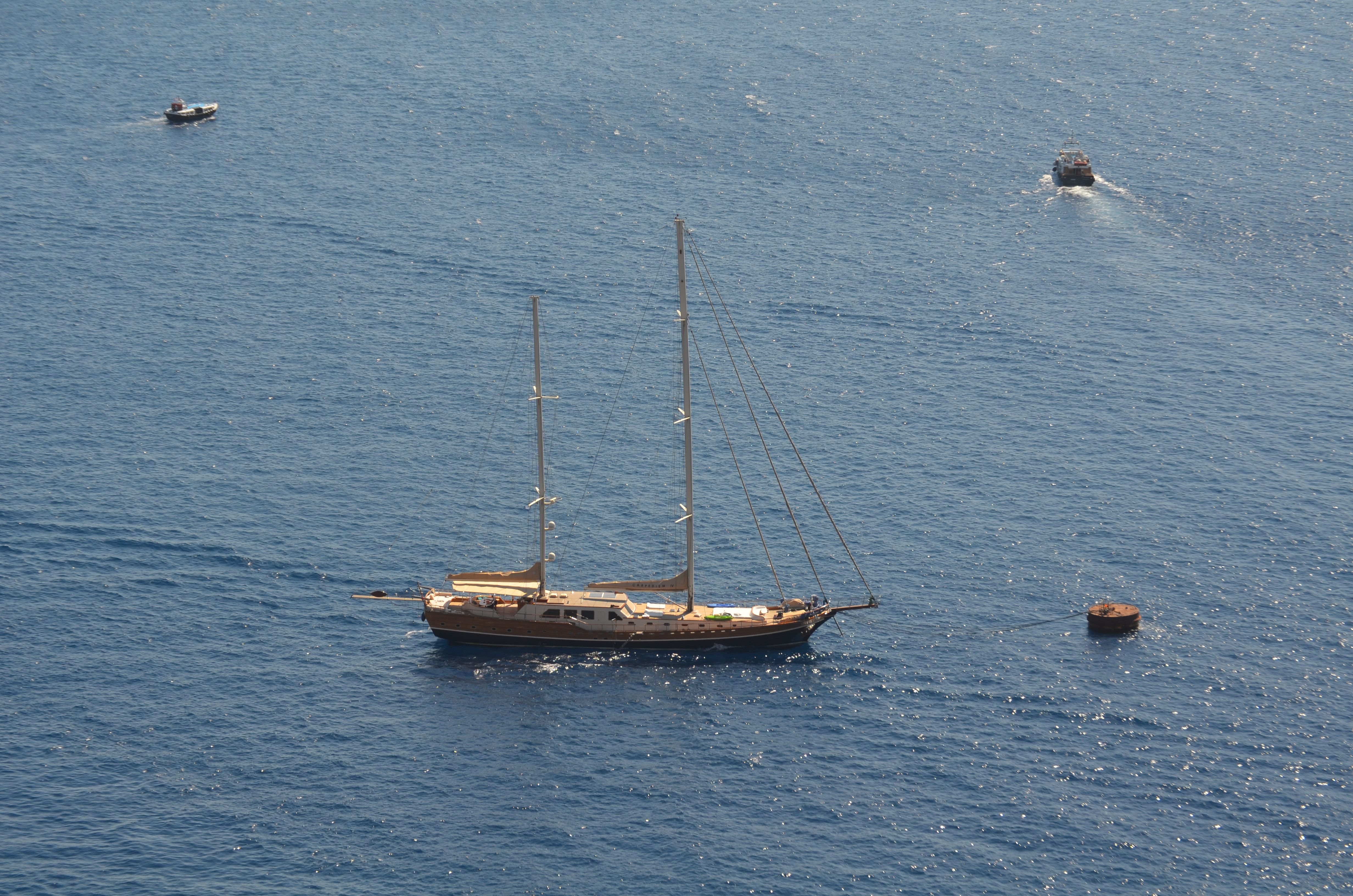 Outstanding Kefalonia Full Day Cruise and Guided Tour from Zakynthos Review 2026 - Aerial view of a yacht sailing in the blue waters near Fira, Greece, showcasing summer tranquility.