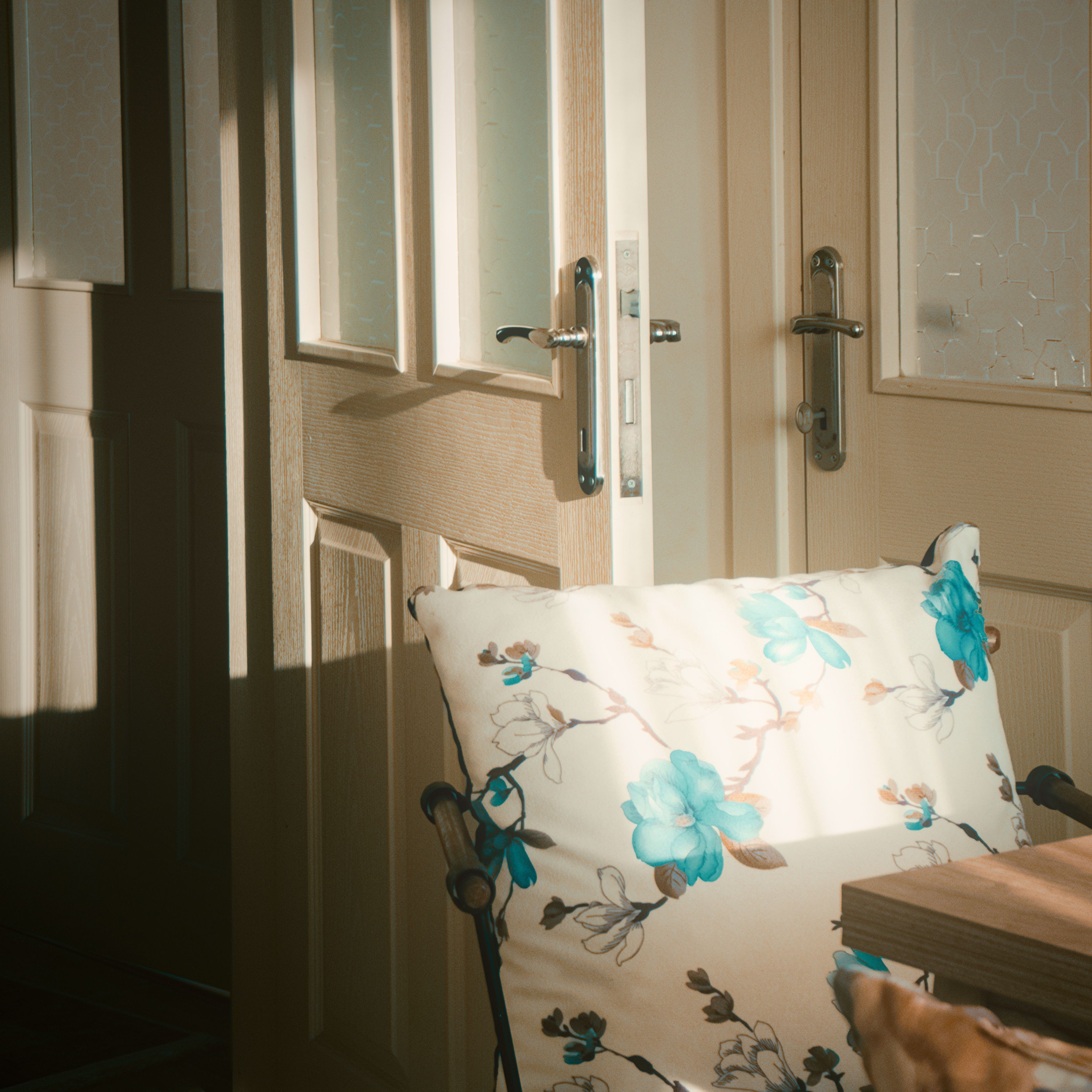 Explore a serene minimalist interior with sunlight streaming on a floral cushion and modern doors.