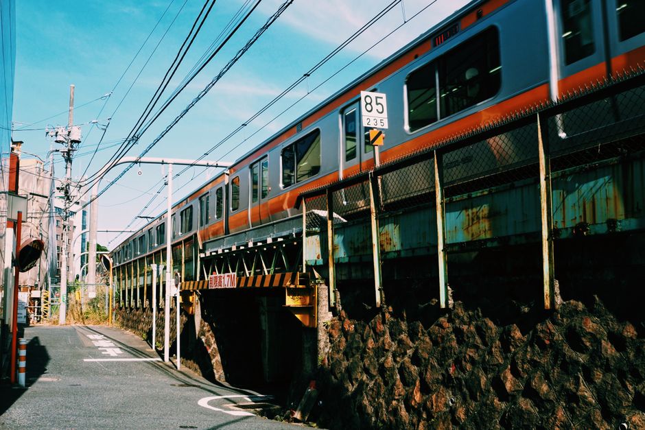 A train passes through an urban street in Tokyo, Japan featuring power lines and city structures.