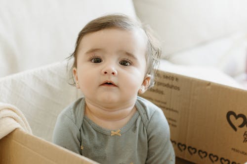 A baby sitting in a cardboard box with a smile