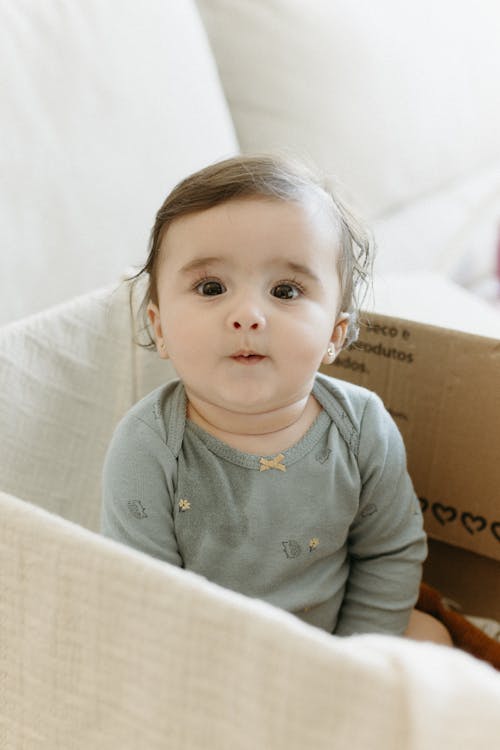 Free A baby sitting in a box with a smile Stock Photo