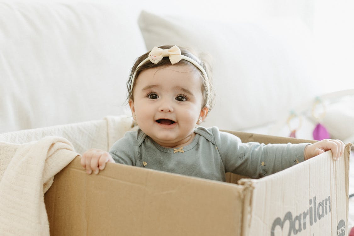 A baby is sitting in a cardboard box