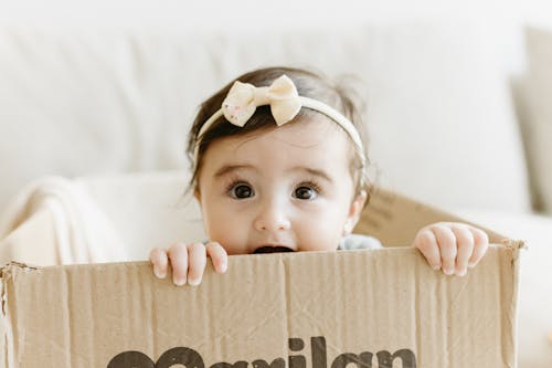 Free A baby girl is sitting in a cardboard box Stock Photo