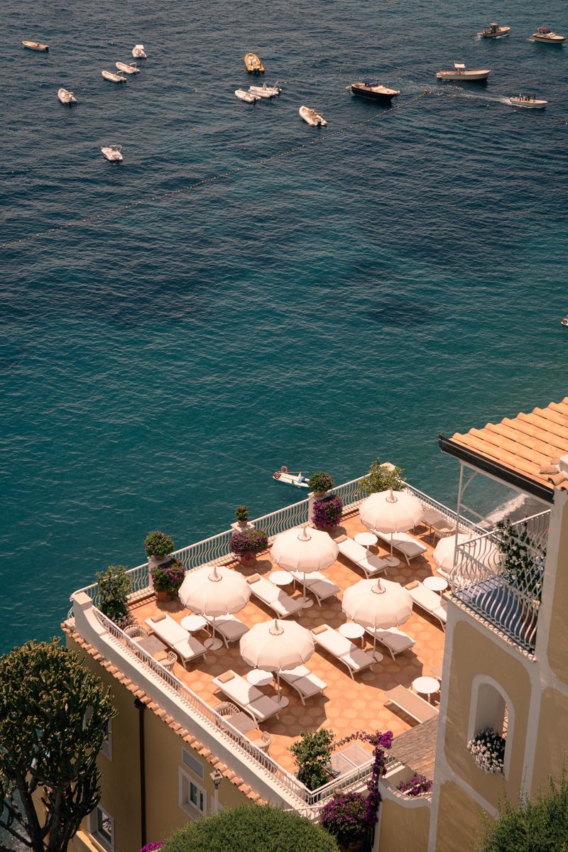 A stunning aerial view of a seaside terrace with elegant umbrellas and a vibrant sea backdrop.