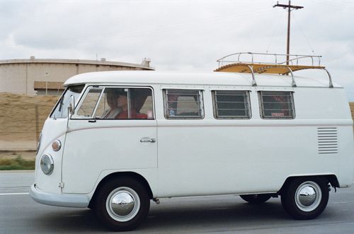 Free Classic white campervan driving on a road, evoking nostalgia of road trips. Stock Photo
