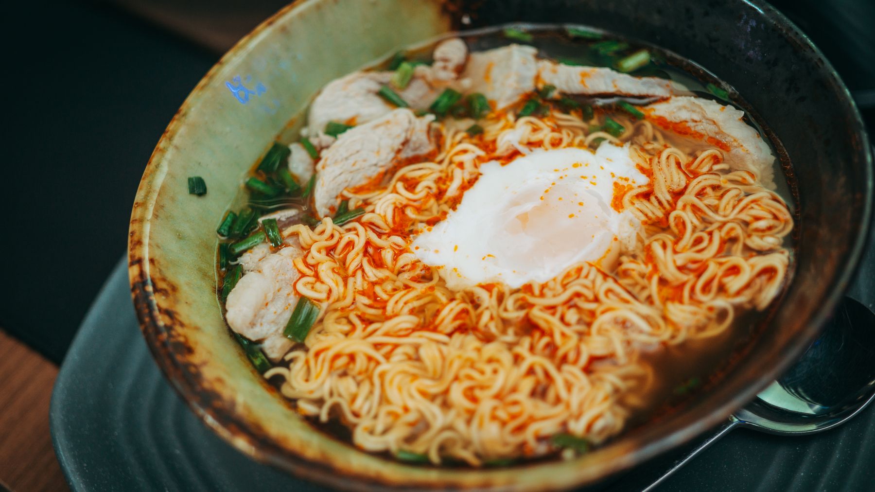 A savory bowl of ramen with poached egg, chicken, and green onions, perfect for a comforting meal.