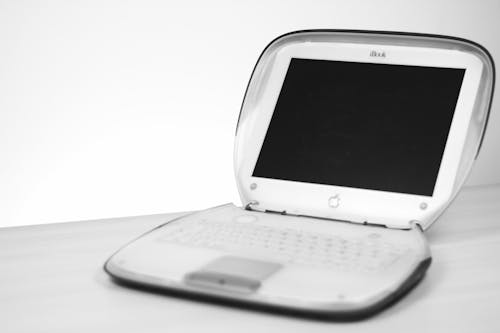 Gratis Laptop Apple Bianco Su Schermo Nero Su Superficie Bianca Foto a disposizione