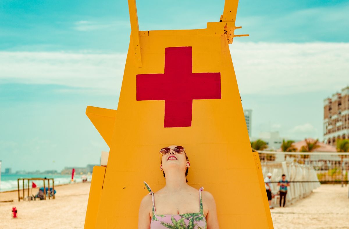 Mujer disfruta un día soleado junto a la colorida torre de salvavidas en la playa de Cancún