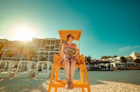 坎昆阳光明媚的海滩背景下，一名身穿花卉泳衣的女子坐在救生塔上