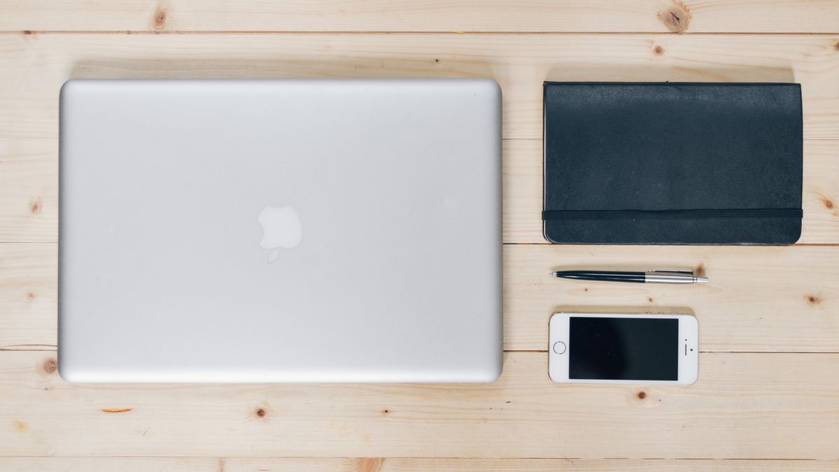 Mesa organizada com notebook, celular, carteira e caderno, representando um sistema pessoal de produtividade financeira