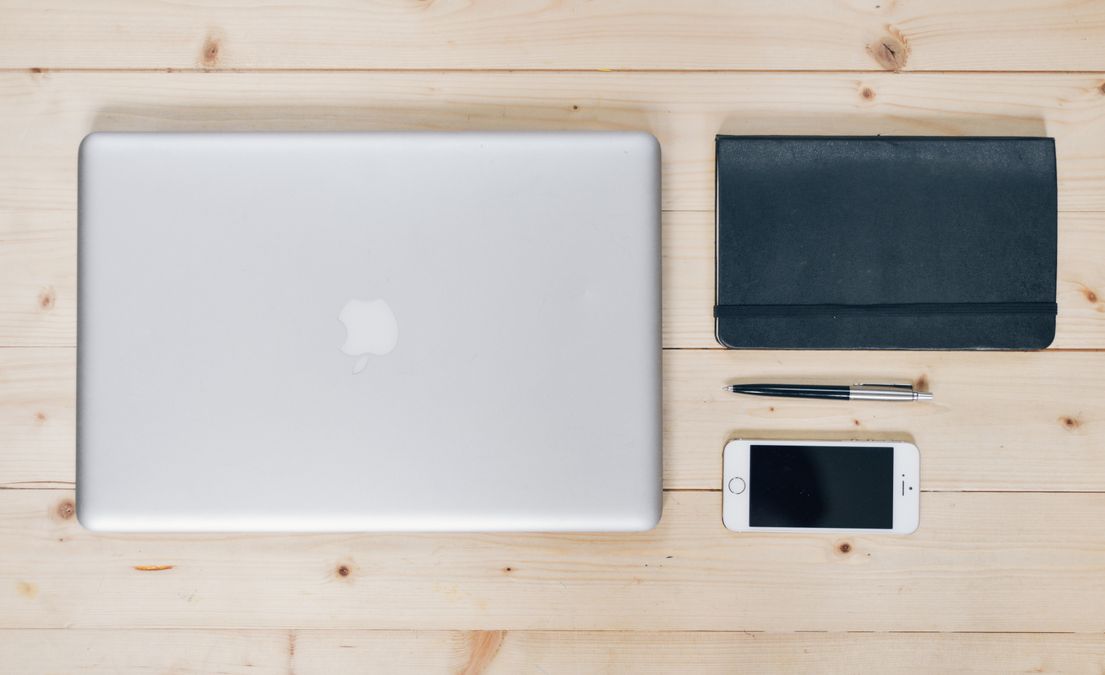 Mesa organizada com notebook, celular, carteira e caderno, representando um sistema pessoal de produtividade financeira