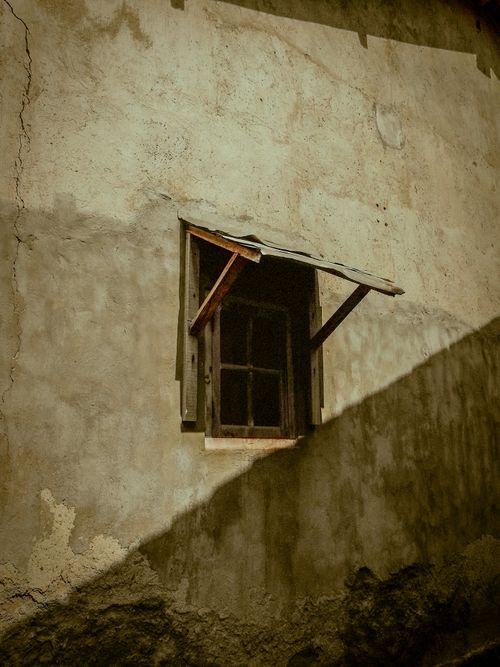 Free Vintage wooden window on a rustic, sunlit wall with shadow play. Stock Photo