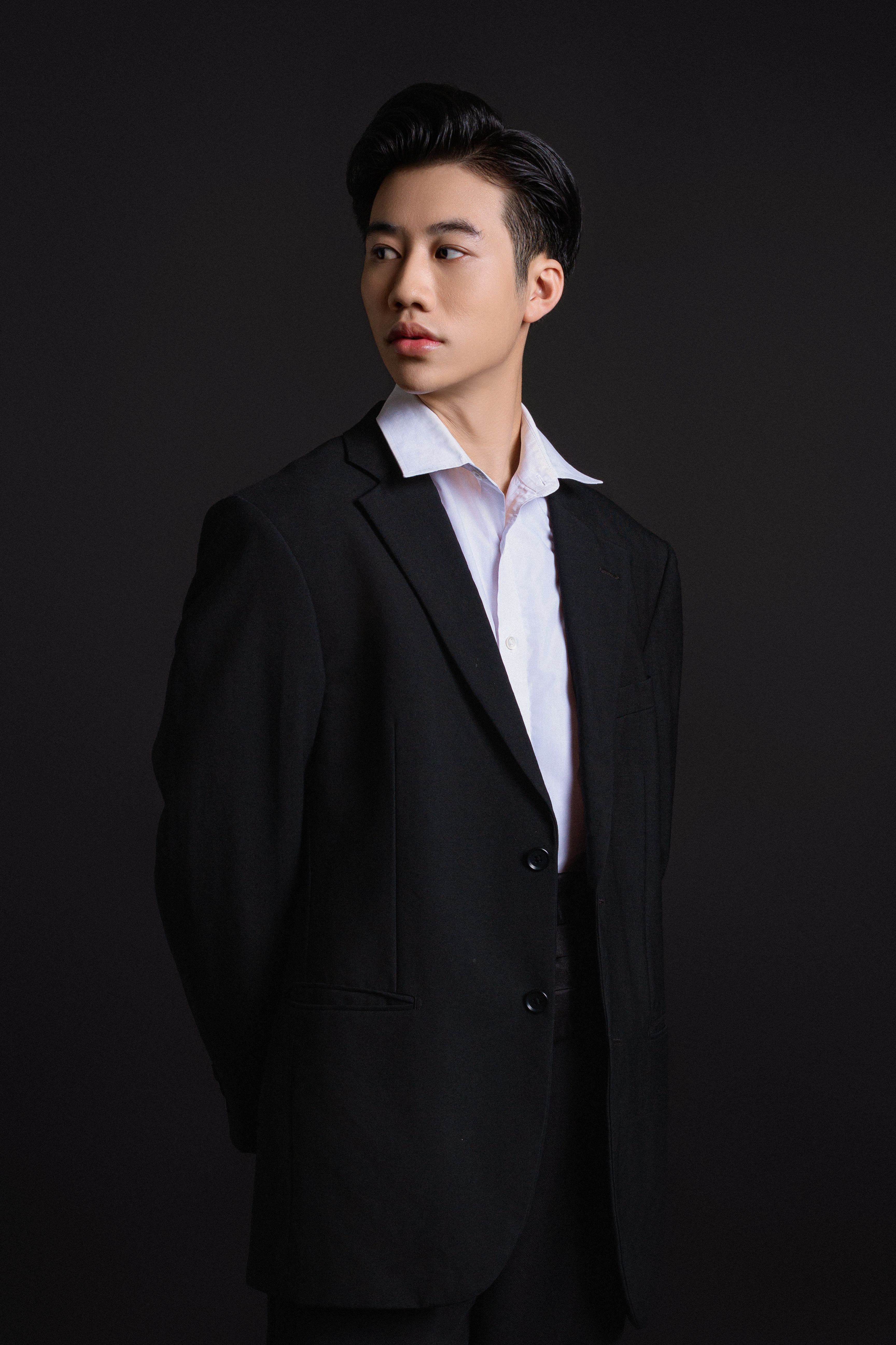 Sophisticated portrait of a young man in a black suit, shot in a studio setting.