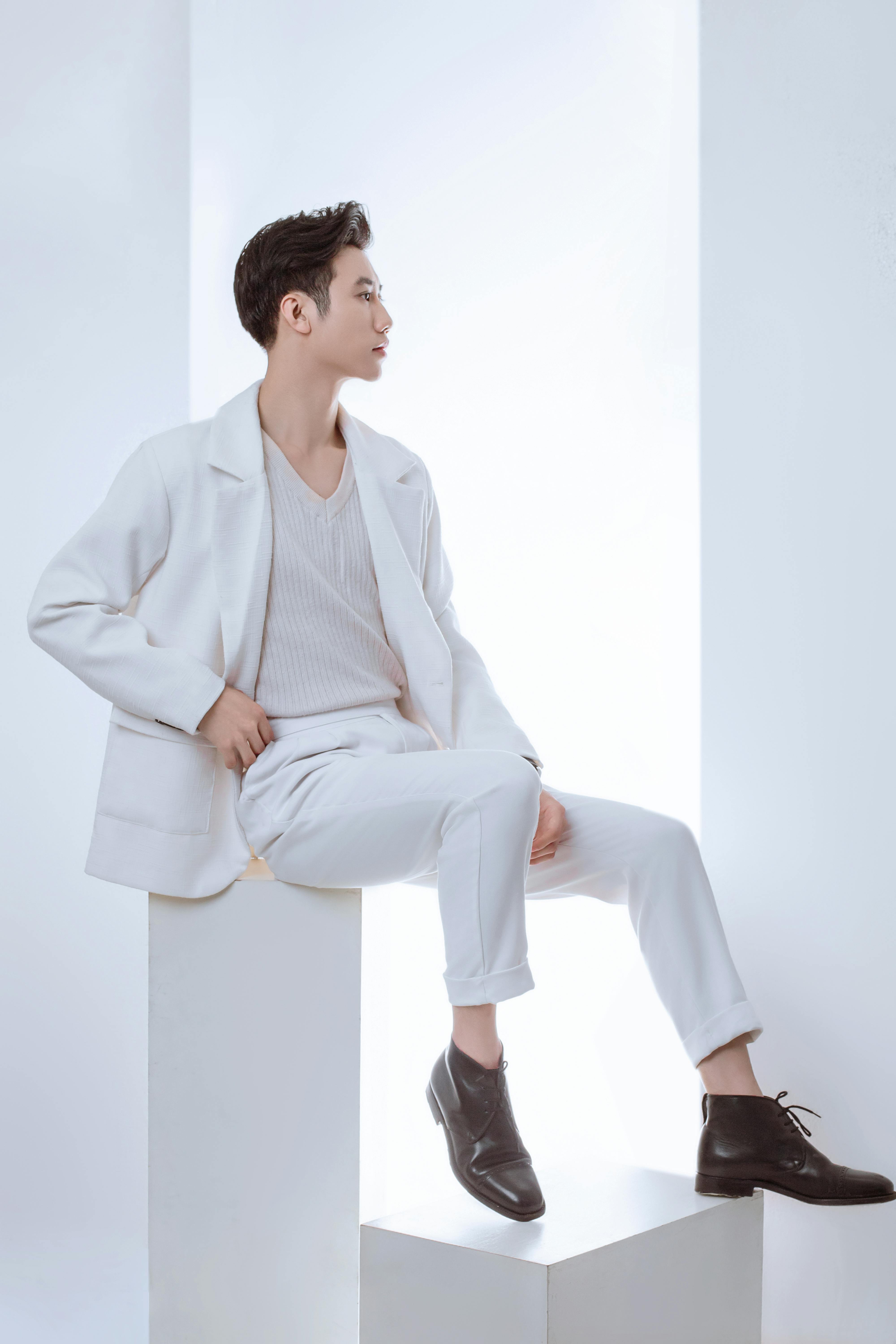 Sophisticated male model posing in a modern, minimalist studio setting wearing stylish white fashion.