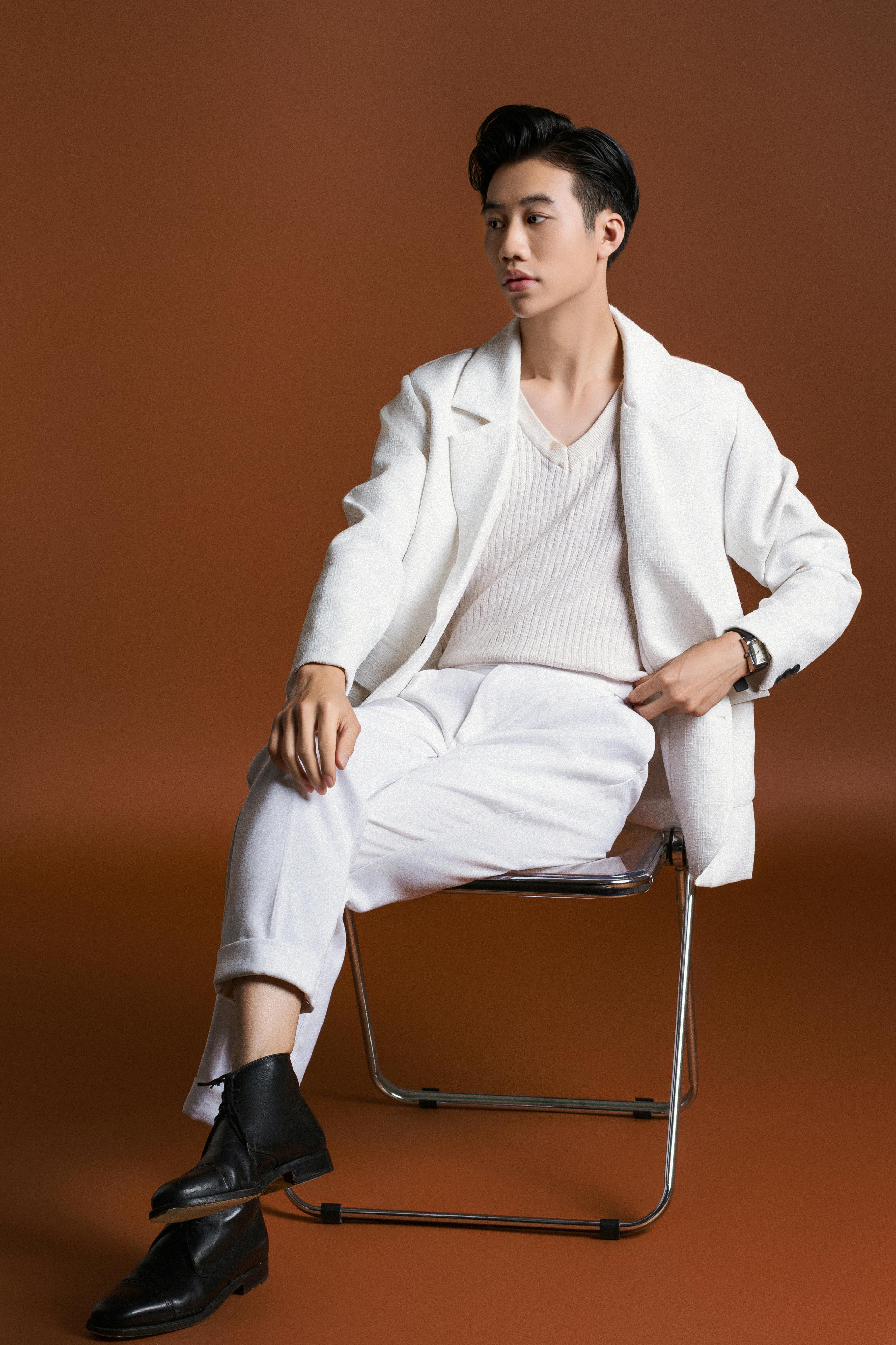Striking portrait of a man in white attire against a brown studio backdrop.
