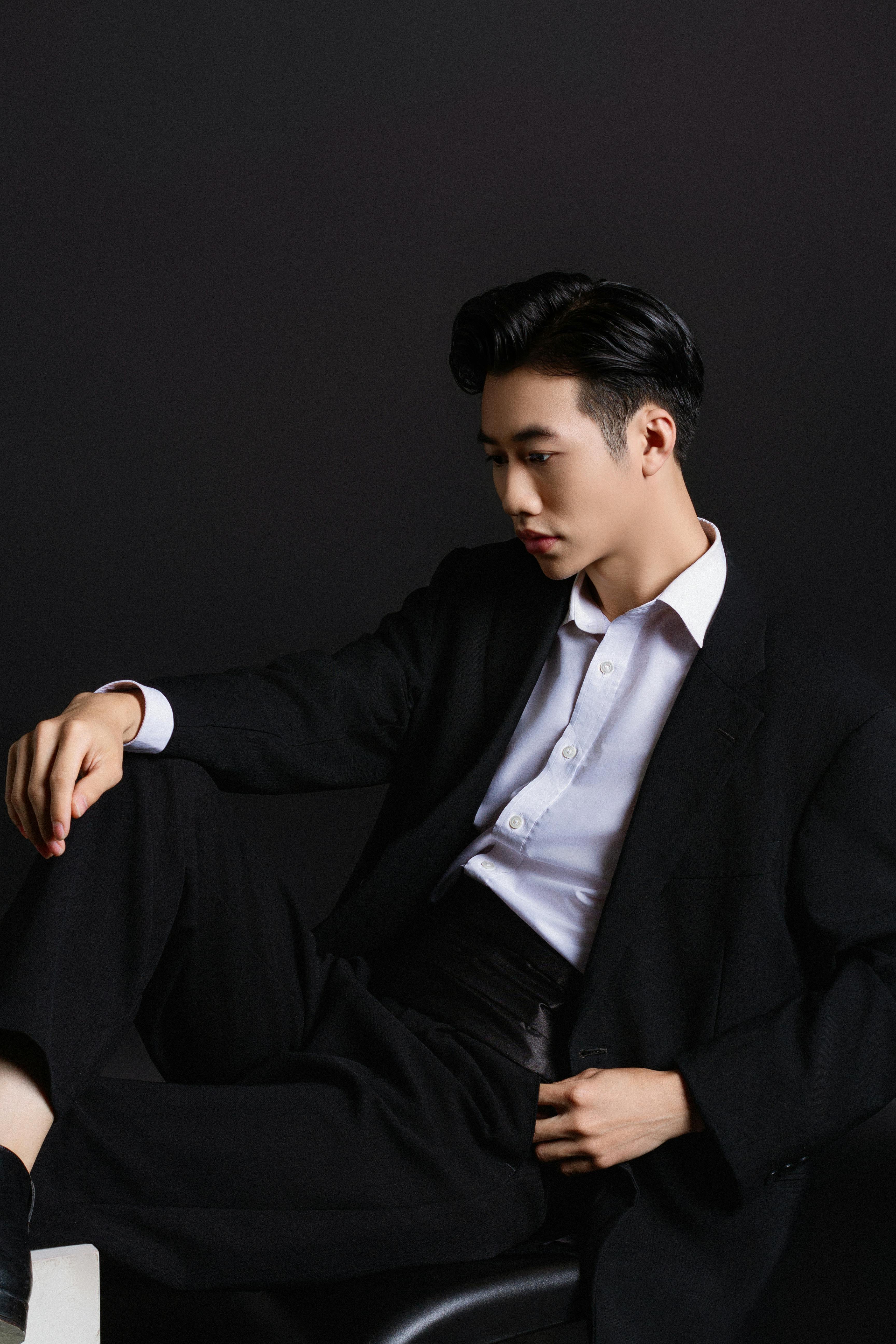 Stylish portrait of an Asian man in a black suit, exuding elegance and modern fashion.