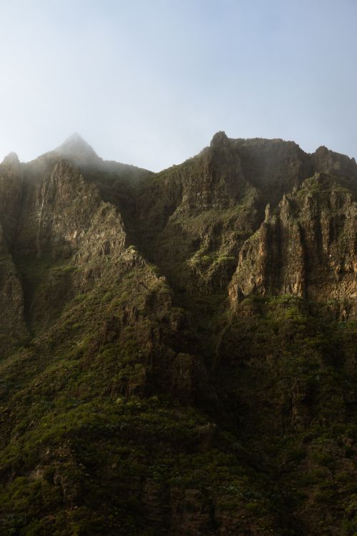 Free Breathtaking view of rugged mist-covered mountain peaks at sunset with soft lighting. Stock Photo