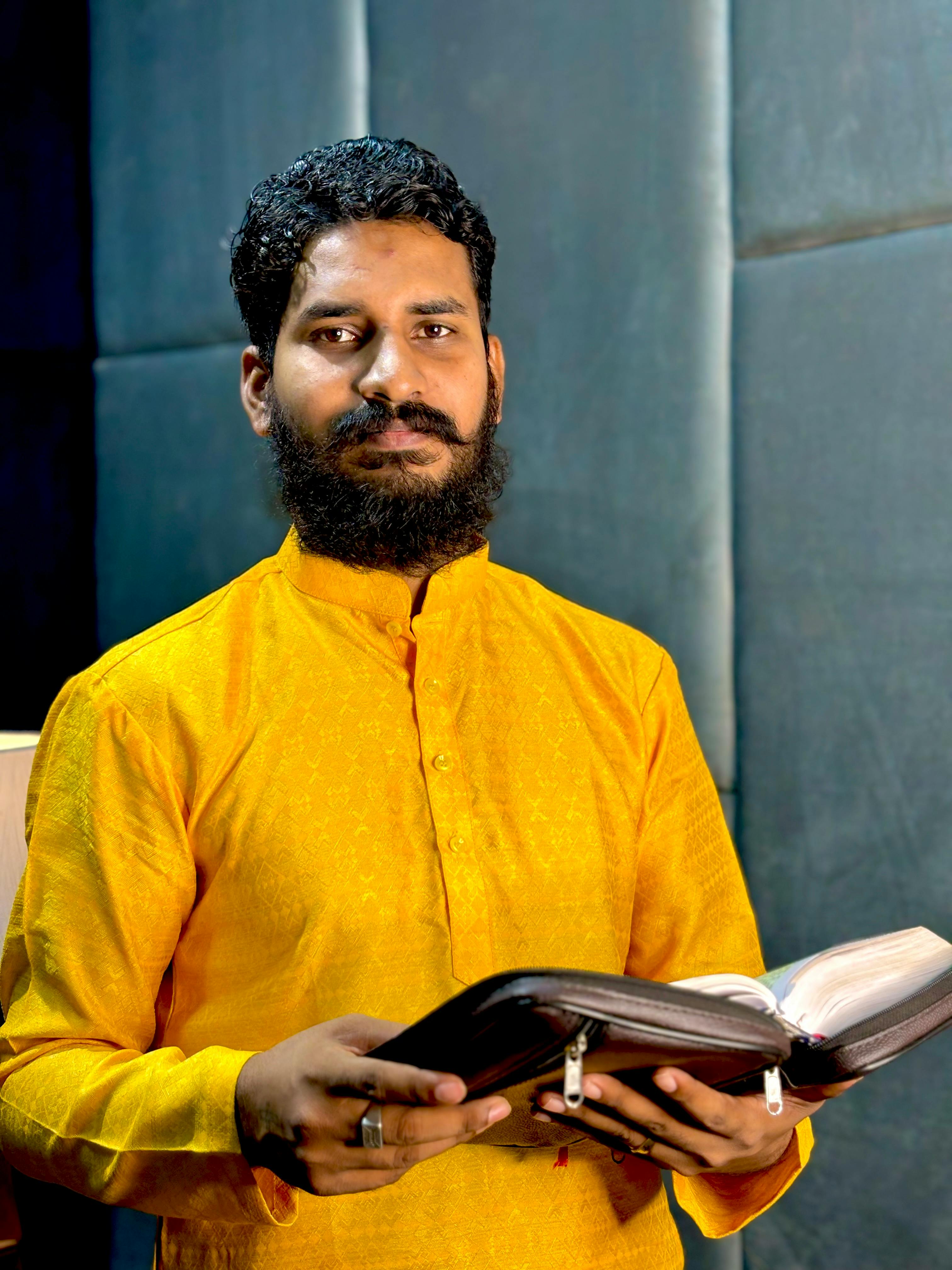 Portrait of a man in yellow clothing holding a book, signifying religious devotion.