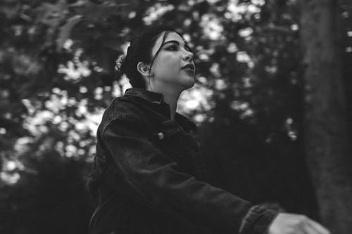 A woman in a black jacket is standing in the woods