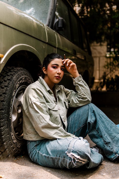 A woman sitting on the ground next to a car