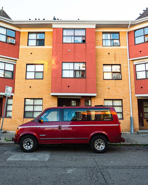 Free Red Van Parked on Curb Beside Building Stock Photo