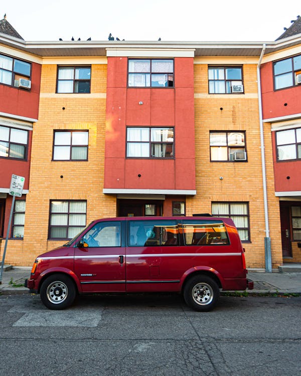 建物の横の縁石に駐車した赤いバン