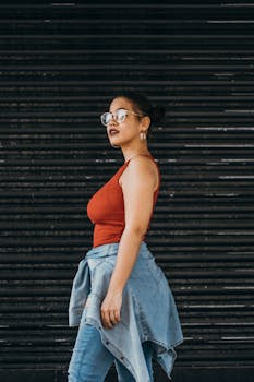 Side view of a woman in casual denim and red top posing outdoors.