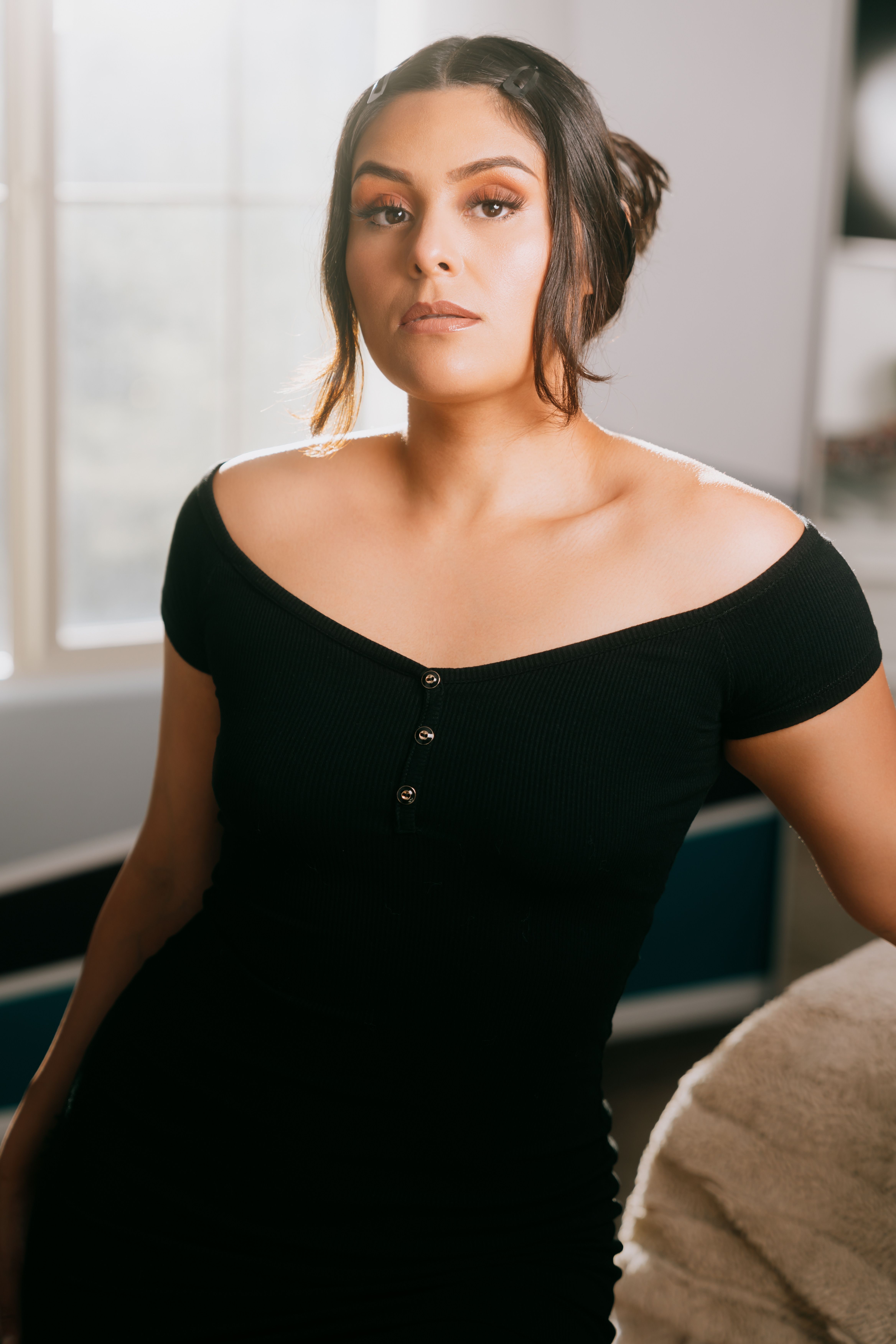 Portrait of a woman in a stylish black dress, exuding elegance and confidence in a well-lit room.