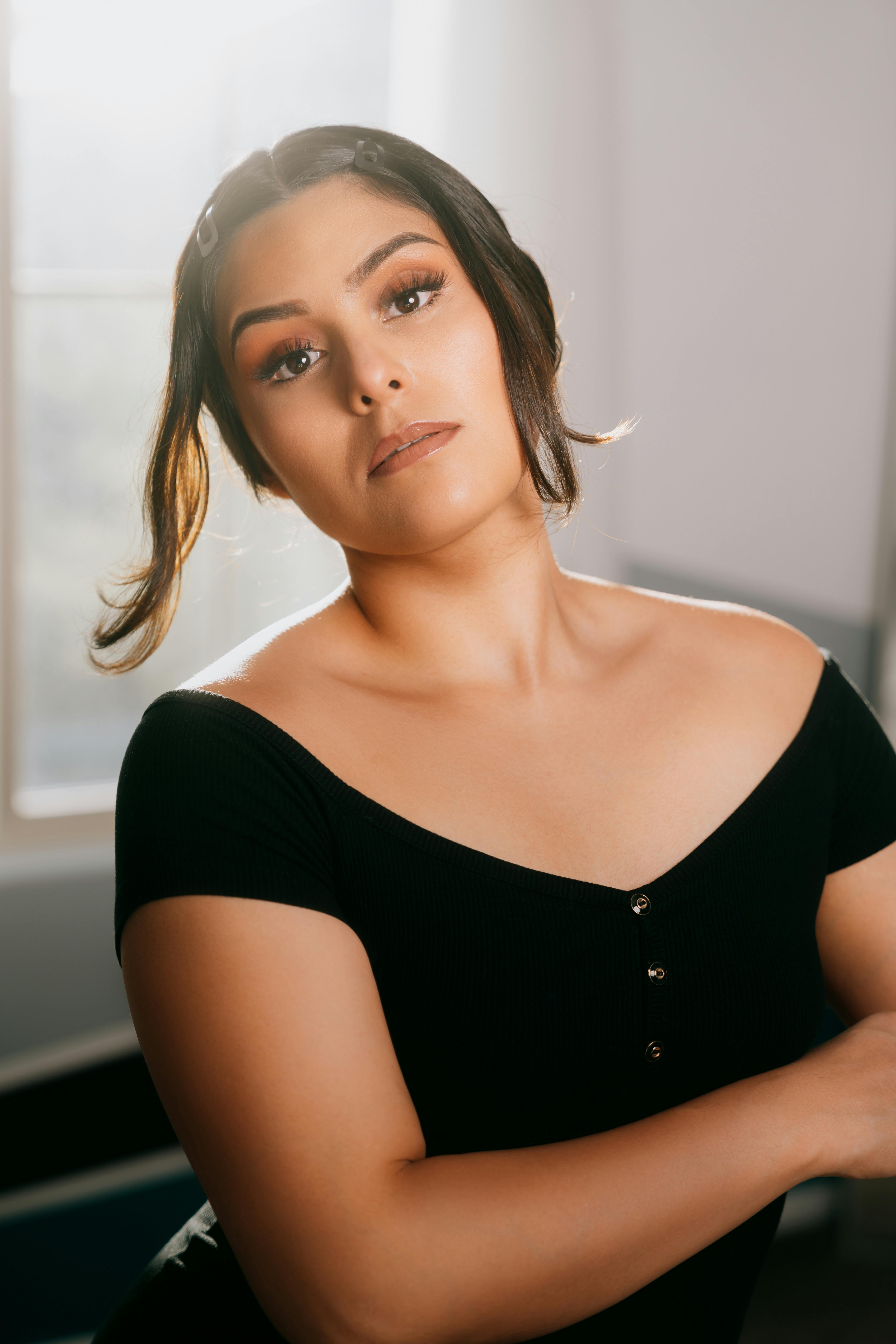 Portrait of a woman in black attire posing gracefully with soft sunlight.