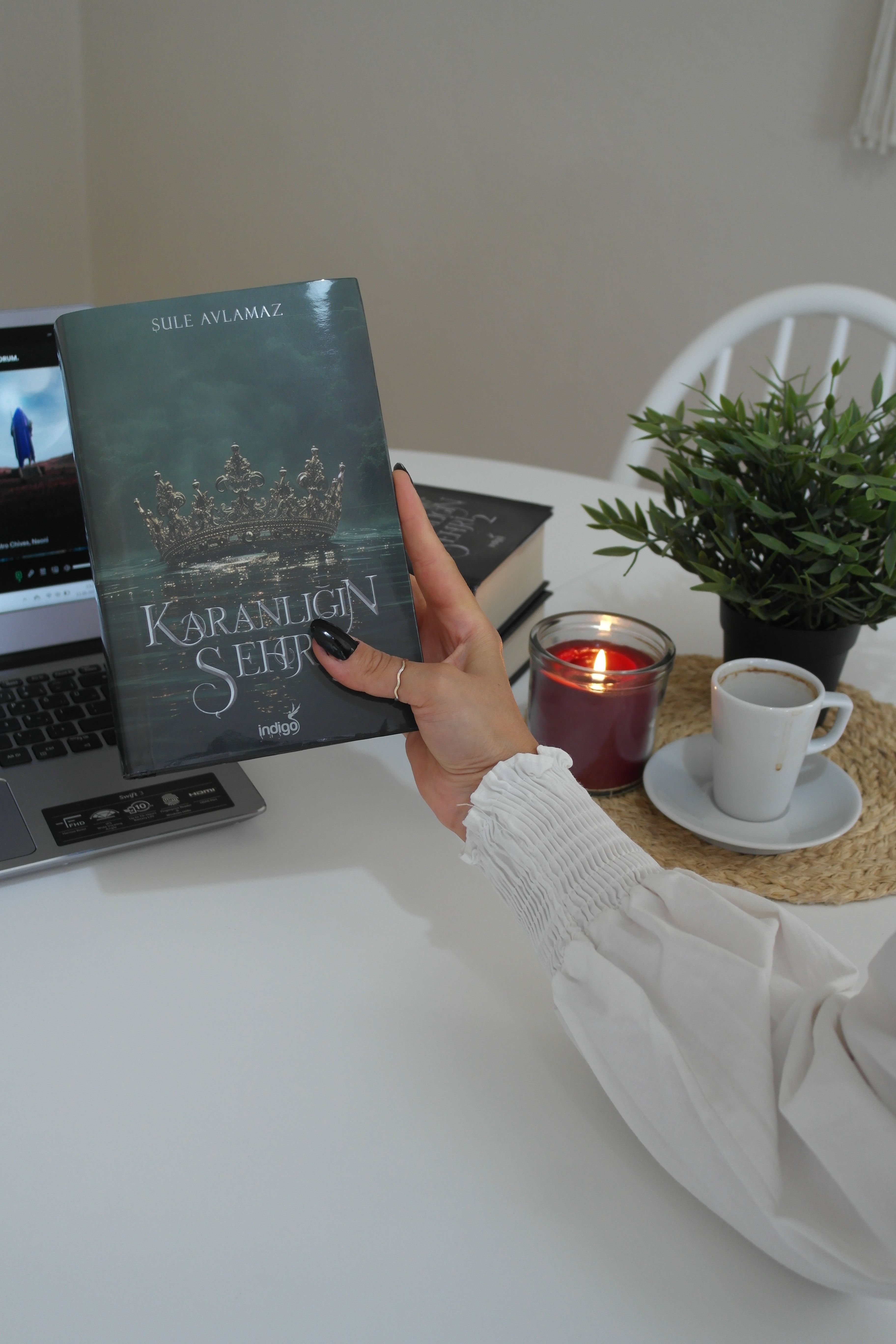 A serene reading setup featuring a book, candle, and cup of coffee indoors.