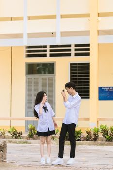 Two teenagers in school uniforms enjoy a fun moment outdoors in an urban setting.
