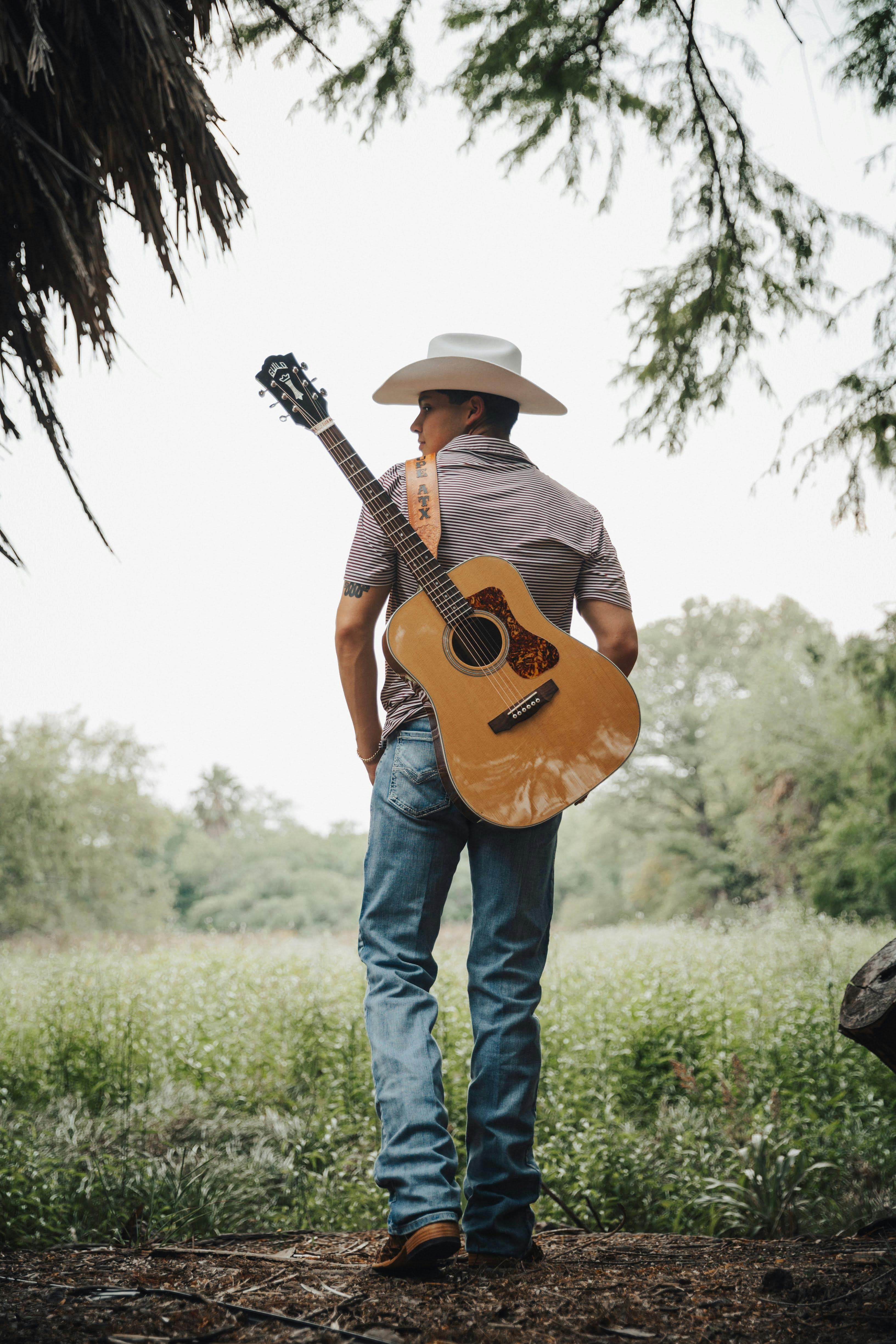 man in hat and with guitar on meadow