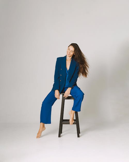 Free A woman sitting on a stool in a blue suit Stock Photo