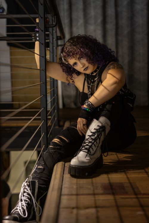 Free Stylish woman in edgy attire sitting by a railing, photographed indoors in Lakeland. Stock Photo